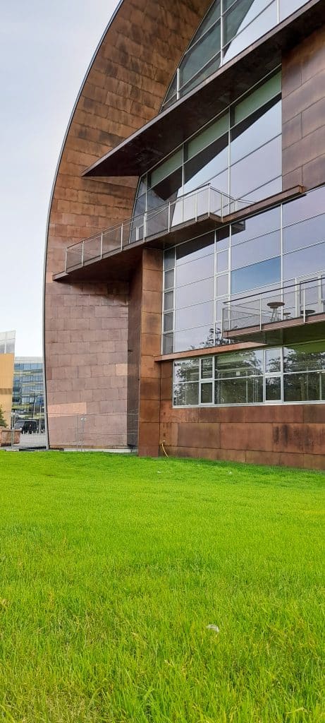 Tuore vihreä siirtonurmi levitettynä modernin, kaarevalinjaisen rakennuksen edustalle – näyttävä yhdistelmä arkkitehtuuria ja maisemointia.