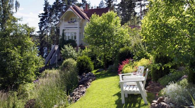Vehreä piha siirtonurmella, istutuksilla ja puutarhakalusteilla – valmis nurmikko viimeistelee kokonaisuuden.