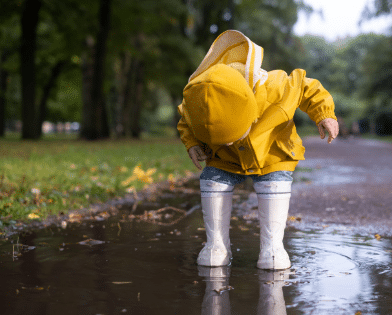 Lapsi leikkii vesilätäkössä ja taustalla näkyy nurmikko